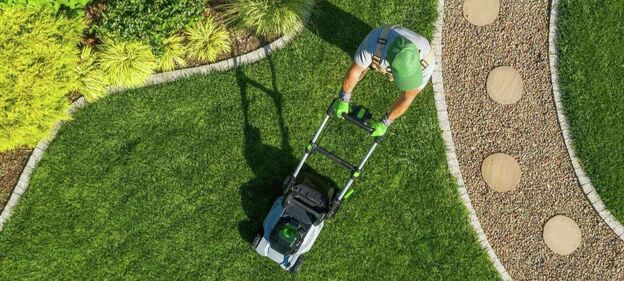 Man mowing a lawn between landscape features
